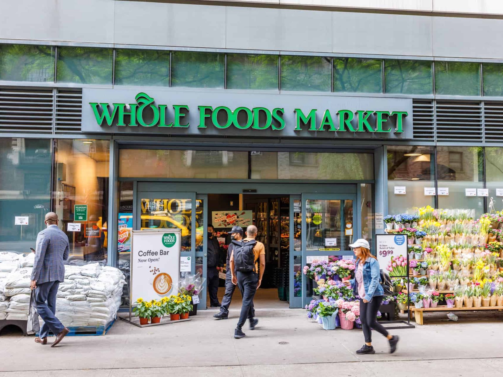 Entrance to Whole Foods Market in Midtown East, New York. Open sliding door with people walking in and out of the store.